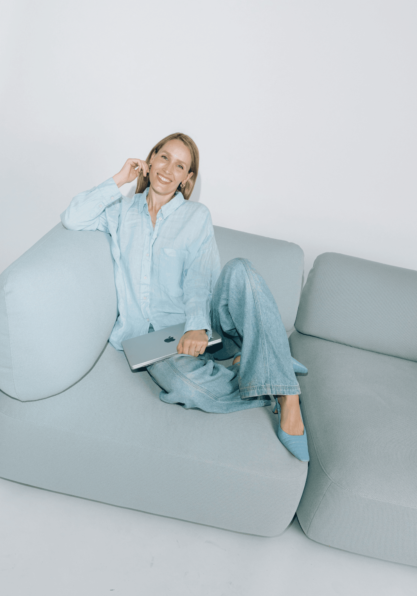 Stella Maria Sorg, Gründerin und AI-Enthusiastin, sitzt mit Laptop auf einem Sofa