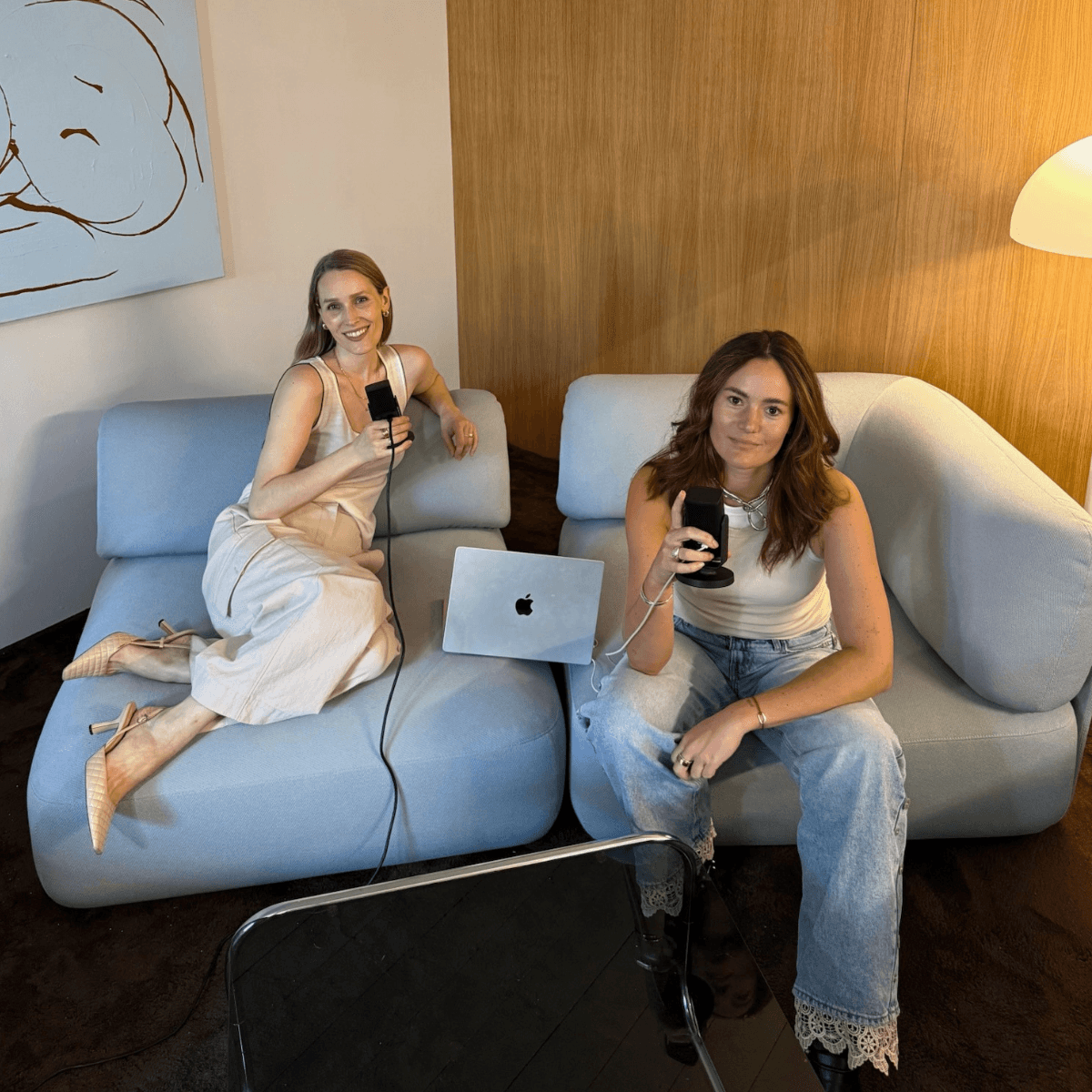 Stella und Sophia nehmen den snacked.ai Podcast auf einem hellblauen Sofa auf